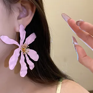 Detailed view of a large pink flower statement earring with golden stamen detail worn on ear