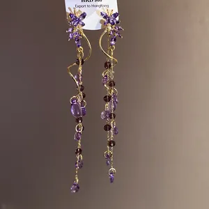 Close-up of purple butterfly tassel earrings with elegant gold-tone wire details.
