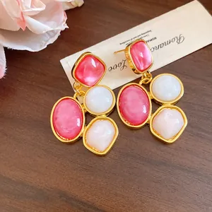 Primo piano di orecchini vintage in resina con pietre rosa e bianche su sfondo di legno