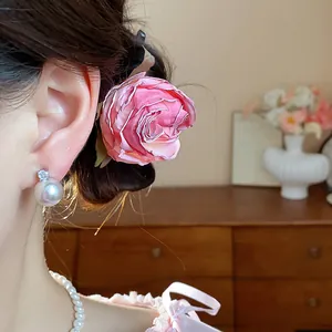 Dettaglio di elegante forcina a fiore in tessuto rosa indossata tra i capelli