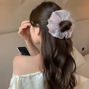Elegant chiffon polka dot scrunchie with lace trim shown on a stylish bun hairstyle