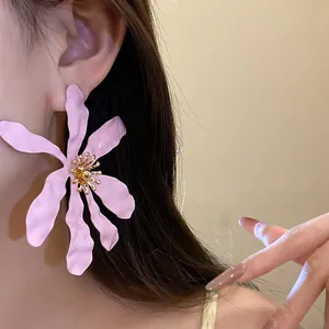 Close-up of large pink flower-shaped earrings with a matte finish for a chic summer look.
