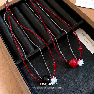 Elegante collana di perline in acciaio inox con fiore di cristallo rosso e sfera.