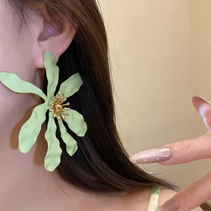 Close-up of large light green flower earring worn by a model for vacation style.