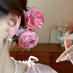 Dettaglio di eleganti forcine a forma di rosa in tessuto rosa per un'acconciatura.