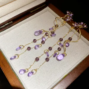 Close-up detail of vintage purple butterfly teardrop tassel earrings in a wooden box