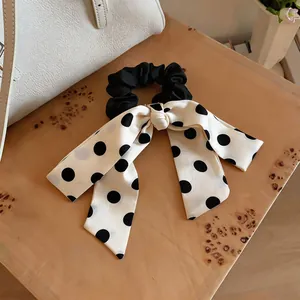 Detail view of the black and white polka dot satin bow scrunchie with long streamers
