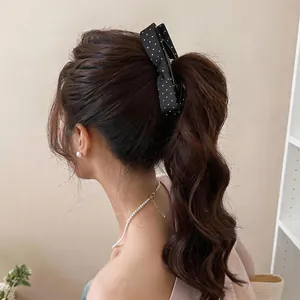Close-up of black and white polka dot bow hair clip on a high ponytail