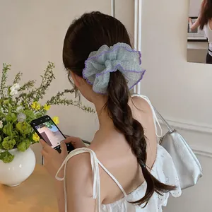 Detailed view of light blue chiffon polka dot scrunchie on braided hair.