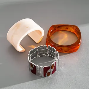Detail shot of resin marble cuff, amber bangle, and metal enamel stretch bracelet.