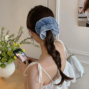Blue gingham oversized fabric scrunchie with white lace trim worn on braided hair