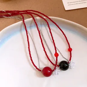 Dettaglio macro di collane di perline rosse e nere con pendenti tondi e fiori