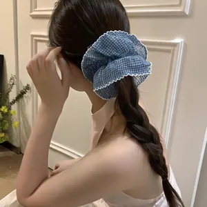 Detailed view of blue gingham scrunchie with lace trim on a braided hairstyle.