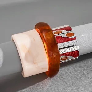 Stack of marbled resin bangles and red enamel metal elastic bracelet on display