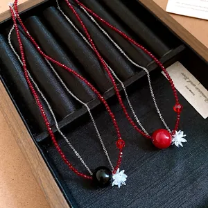 Dettaglio di due collane di perline con pendenti a fiore in un vassoio nero.