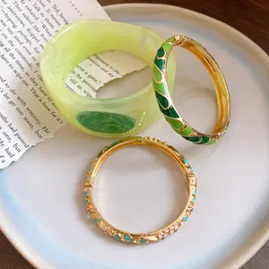 Detailed view of colorful enamel drip oil gold bangles and green resin bracelet