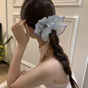 Detail of oversized polka dot chiffon scrunchie with ruffled flower edges on braid