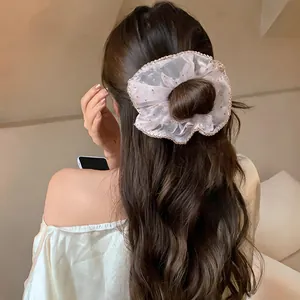 Close-up view of a delicate chiffon scrunchie with polka dots and lace trim on long hair