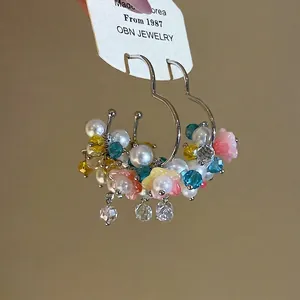 Fresh and sweet floral hoop earrings featuring colorful beads and white pearls on gold hoops.