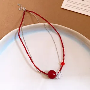 Vista dettagliata della collana di perle rosse in acciaio con un ciondolo a fiore