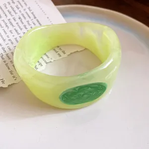 Macro detail of light yellow marbled resin bangle with elegant dark green swirl pattern