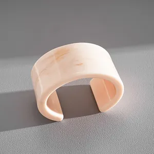 Close-up view showing the natural marbled texture of this light pink resin cuff bangle