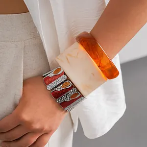 Close-up of a stylish enamel metal bracelet and geometric resin bangles on a model's arm