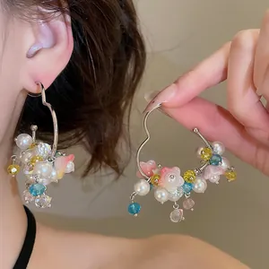 Close-up of sweet heart-shaped hoop earrings decorated with colorful pearls and flower beads