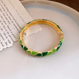 Detail of gold-plated buckle bracelet featuring green enamel dripping oil patterns