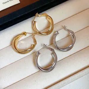 Close-up view of twisted 18K gold plated and silver hoop earrings on a display tray
