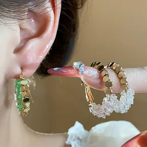 Close-up of 14K gold plated hoop earrings with colorful crystal accents and silver needles
