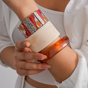 Close-up of three stacked bangles including metal oil-drop and marble resin styles.