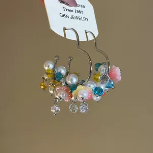 Close-up of sweet summer hoop earrings featuring colorful flowers and glossy pearls.