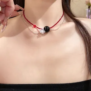 Primo piano di collana a doppio strato con perle rosse, sfera nera e ciondolo fiore