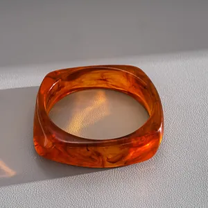 Macro view of translucent amber resin bangle with elegant marble swirl pattern