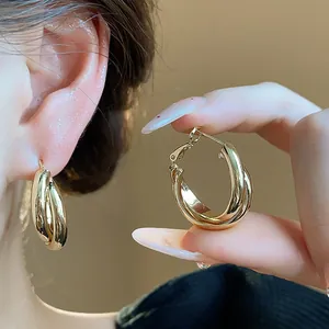 Detail view of 18K gold-plated interlocking hoop earrings with minimalist light luxury style