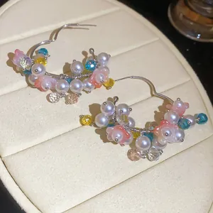 Detail shot of colorful beaded hoop earrings with pearls and pink flowers.
