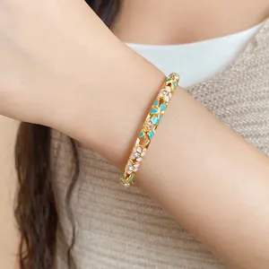 Close-up of elegant floral enamel gold-tone bangle with sparkling crystals on wrist