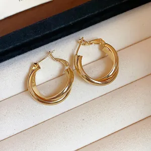 Macro detail of 18K gold plated twisted hoop earrings in a beige display box