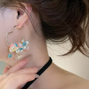 Close-up of sweet heart-shaped hoop earrings with colorful pearl flower charms