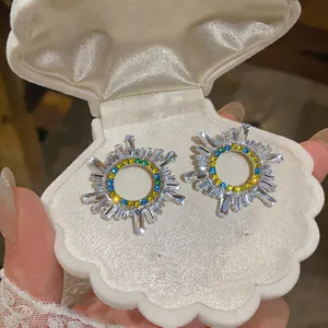 Dettaglio ravvicinato di orecchini vintage con pietre blu e gialle in scatola a conchiglia