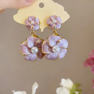 Detaillierte Nahaufnahme von eleganten lila Emaille-Blumenohrringen mit zentralen weißen Perlen