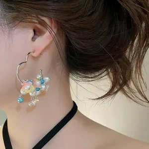 Detail view of sweet heart hoop earrings with pearls and colorful flowers on model's ear