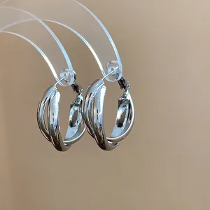 Detail view of minimalist silver needle hoop earrings with a twisted metallic design