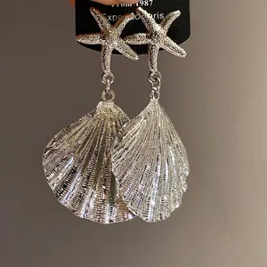 Elegant silver metal pleated seashell and starfish earrings for a resort vacation style.