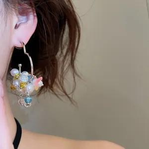 Close-up of a sweet heart-shaped hoop earring with pearls and colorful beads on an ear.