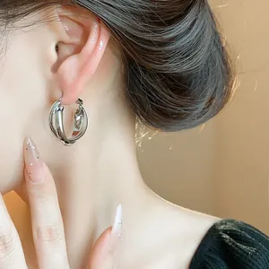 Close-up of minimalist silver intertwined triple hoop earrings on model