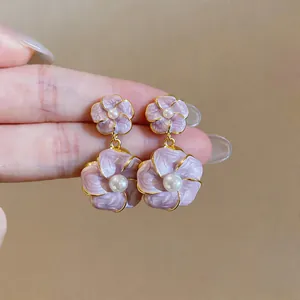 Detaillierte Nahaufnahme von eleganten lila Emaille-Blumenohrringen mit Perlen und Gold.