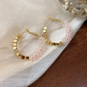 Close-up detail of 14K gold plated hoop earrings featuring pink faceted crystals and metal beads