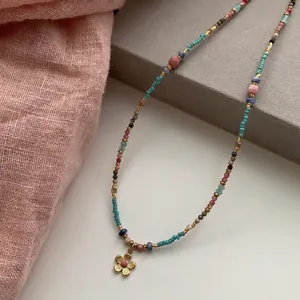 Retro ethnic style stainless steel beaded necklace with a small flower pendant detail.